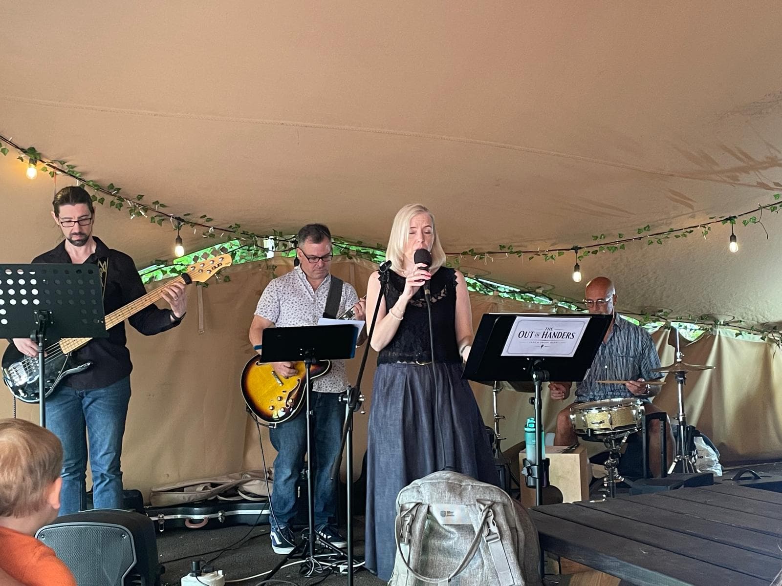 The full band performing under festoon lights